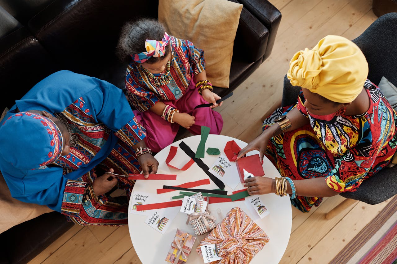 A joyful family making crafts for Kwanzaa, dressed in colorful traditional clothes.